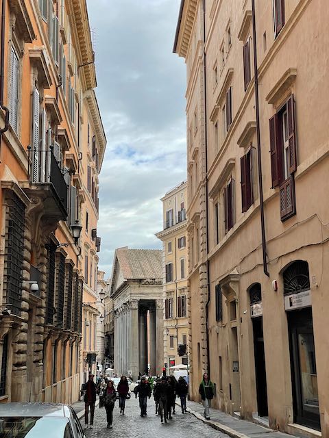 People walking in a street in Rome with historic buildings on either side